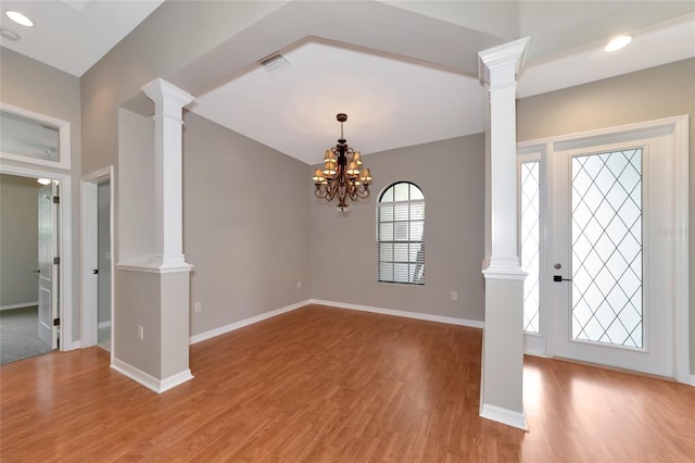 entryway featuring hardwood / wood-style flooring, ornate columns, and an inviting chandelier