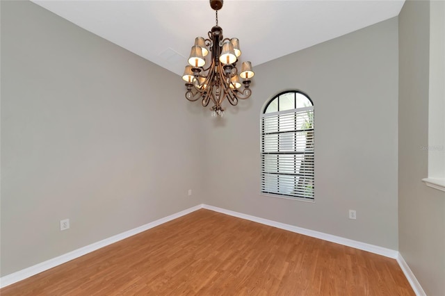 spare room featuring hardwood / wood-style flooring and a notable chandelier