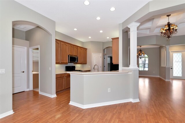 kitchen featuring stove, light wood-type flooring, ornate columns, a chandelier, and coffered ceiling