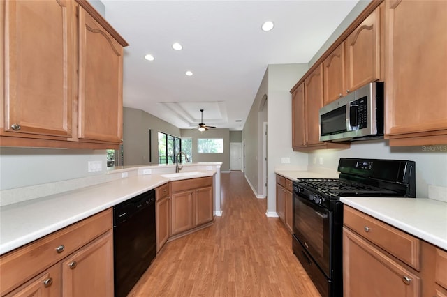 kitchen with ceiling fan, light hardwood / wood-style floors, black appliances, a raised ceiling, and sink