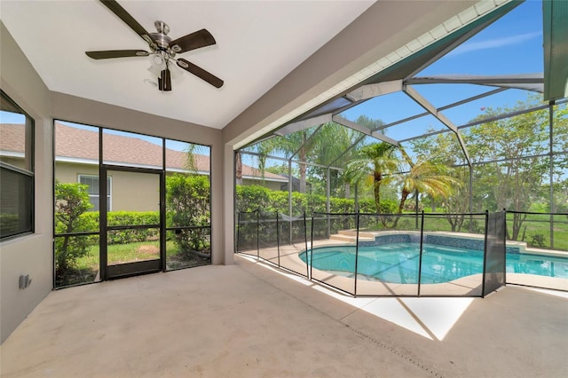 view of pool featuring glass enclosure, a patio area, and ceiling fan