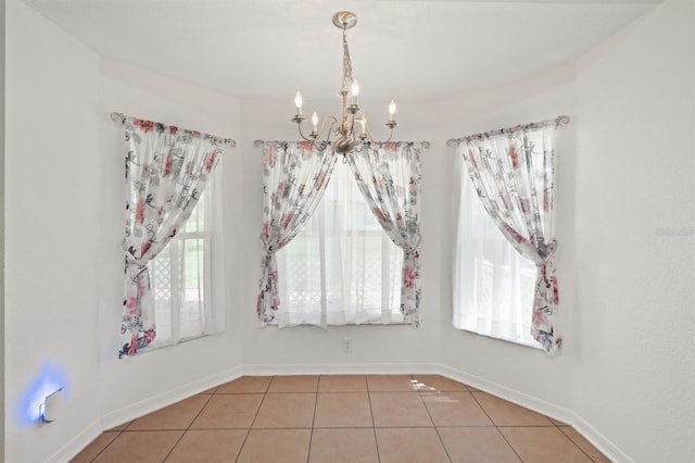 tiled empty room featuring a notable chandelier