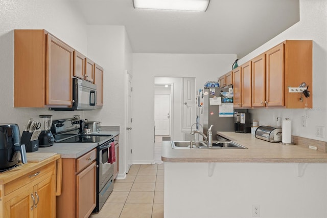 kitchen with kitchen peninsula, electric range, sink, stainless steel refrigerator, and light tile patterned floors