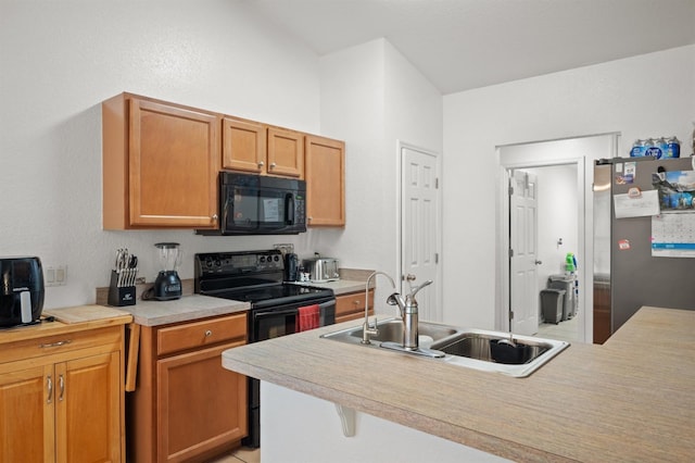 kitchen featuring a breakfast bar, sink, black appliances, and kitchen peninsula