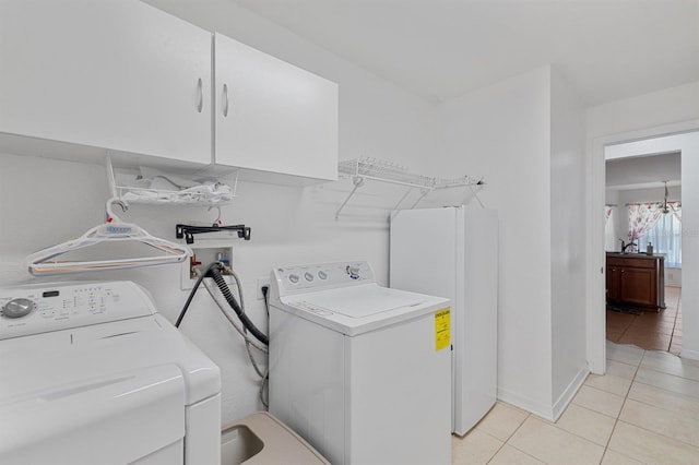 clothes washing area featuring cabinets, light tile patterned floors, and independent washer and dryer