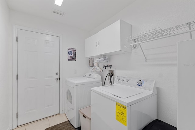 laundry room featuring separate washer and dryer, cabinets, and light tile patterned floors