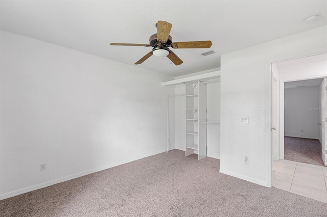 unfurnished bedroom with a closet, light colored carpet, and ceiling fan