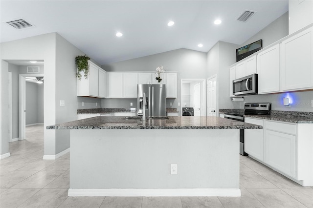 kitchen with light tile patterned floors, stainless steel appliances, lofted ceiling, and a center island with sink