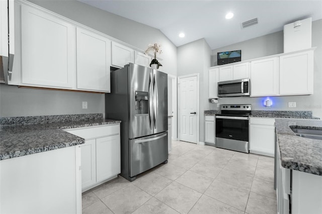 kitchen with light tile patterned floors, stainless steel appliances, vaulted ceiling, and white cabinets