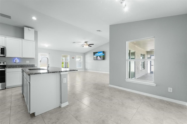 kitchen featuring light tile patterned flooring, electric range oven, a center island with sink, and vaulted ceiling