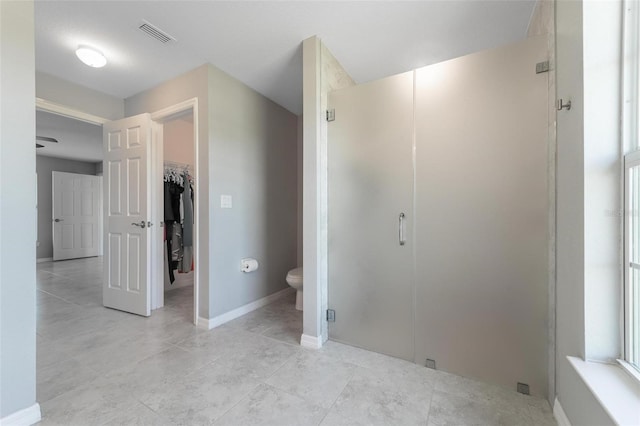 bathroom with tile patterned floors, toilet, and a shower with door