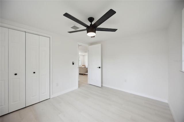 unfurnished bedroom with ceiling fan, a closet, and light wood-type flooring