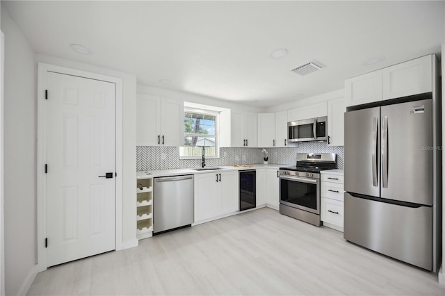 kitchen with wine cooler, sink, white cabinetry, and stainless steel appliances