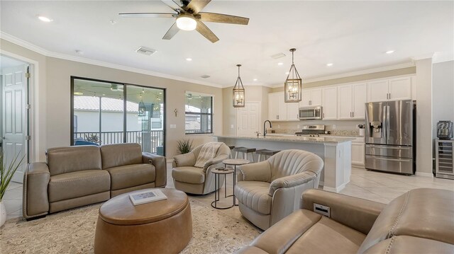 tiled living room with ceiling fan, sink, and crown molding