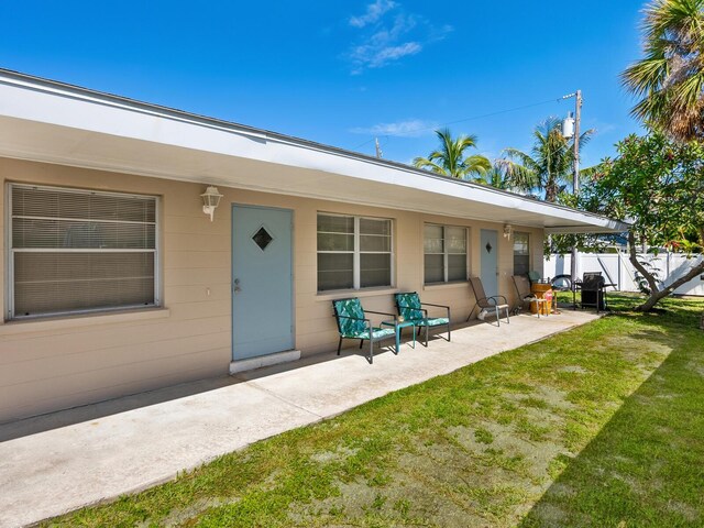 back of property with a yard and a patio area