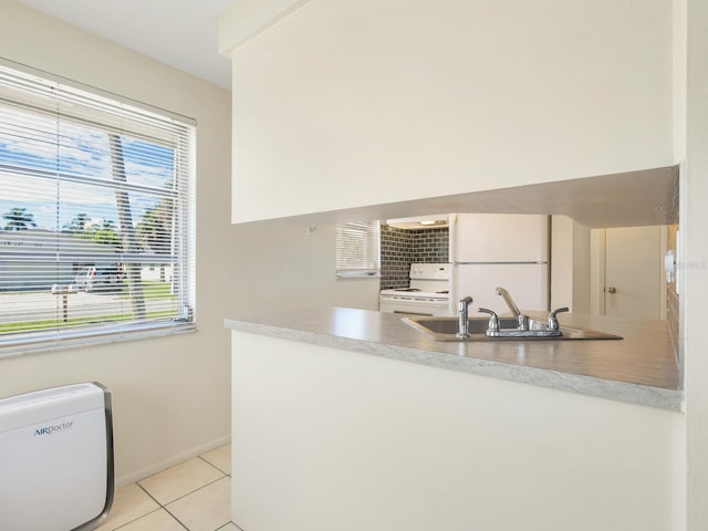 kitchen with sink, light tile patterned floors, kitchen peninsula, and white appliances