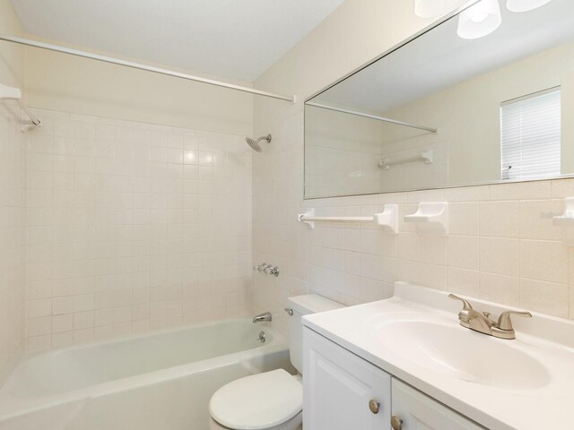 full bathroom featuring vanity, tile walls, decorative backsplash, tiled shower / bath combo, and toilet