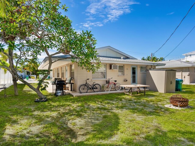 back of house featuring a fire pit, a yard, and a storage unit