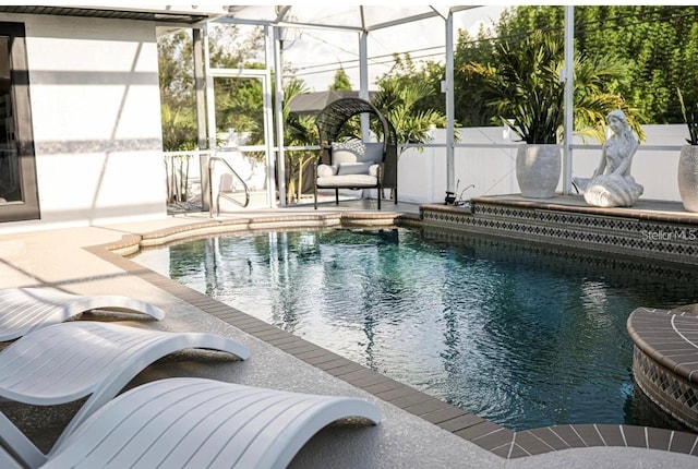 view of pool with a patio area and glass enclosure