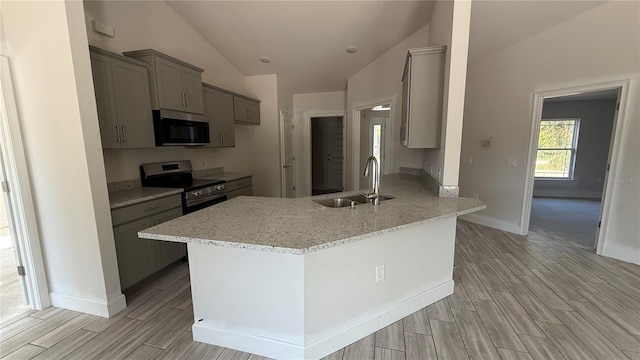 kitchen with lofted ceiling, sink, light stone counters, kitchen peninsula, and stainless steel appliances