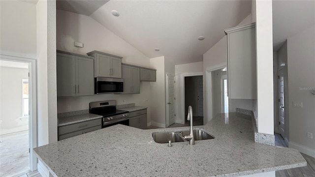 kitchen featuring light stone counters, kitchen peninsula, sink, and appliances with stainless steel finishes