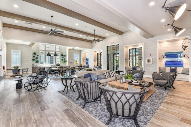 living room featuring beamed ceiling, ceiling fan, and light hardwood / wood-style floors