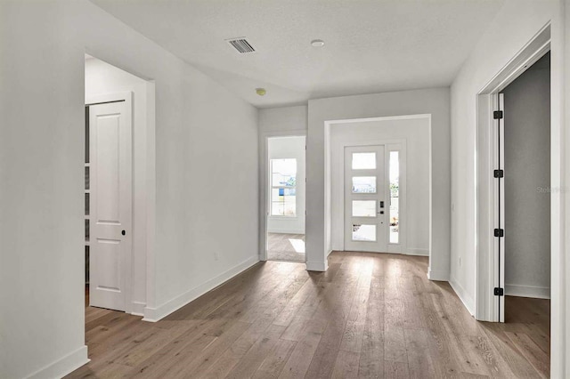 foyer entrance featuring french doors, a textured ceiling, and light hardwood / wood-style flooring