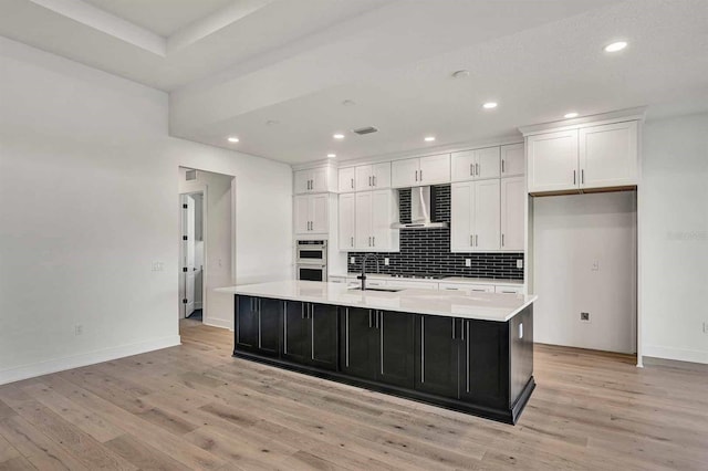 17931 Palmiste Dr, Bradenton, FL 34202 - kitchen featuring wall chimney exhaust hood, white cabinetry, light wood-type flooring, decorative backsplash, and recessed lighting