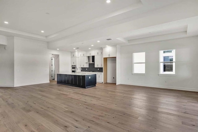 unfurnished living room featuring hardwood / wood-style flooring, a raised ceiling, and sink