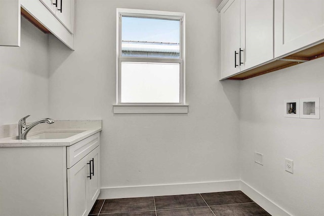 laundry area featuring cabinets, sink, dark tile patterned floors, and washer hookup