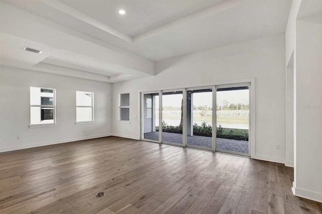 unfurnished room with hardwood / wood-style floors and a tray ceiling