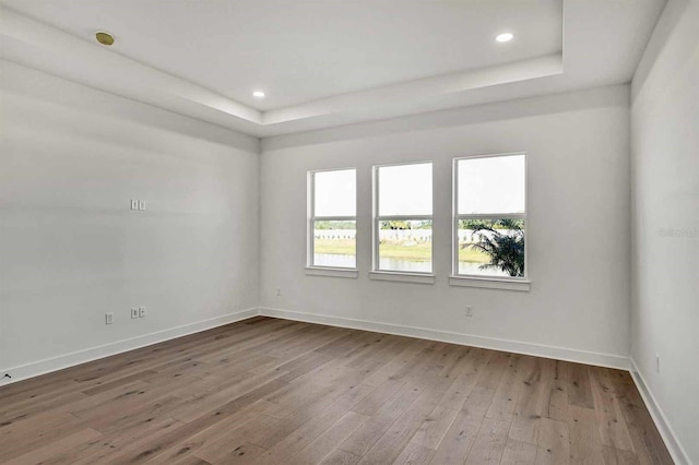 unfurnished room featuring hardwood / wood-style flooring and a tray ceiling