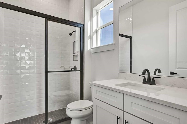 bathroom with vanity, toilet, and a shower with shower door