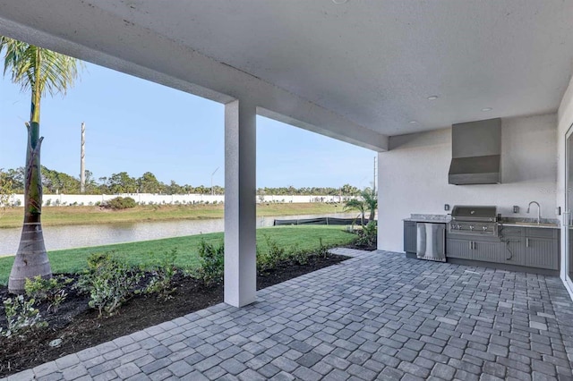 view of patio / terrace featuring an outdoor kitchen, a water view, sink, and grilling area