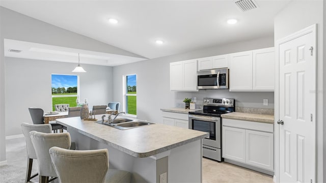 kitchen featuring appliances with stainless steel finishes, decorative light fixtures, sink, white cabinets, and a kitchen island with sink