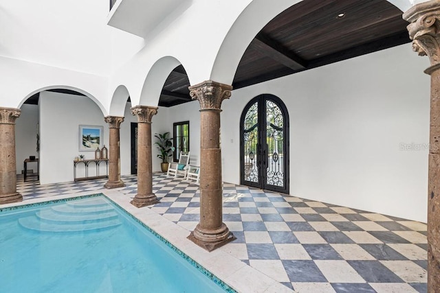 view of swimming pool with decorative columns and french doors