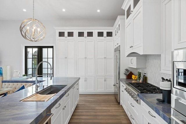 kitchen with decorative light fixtures, white cabinetry, and sink