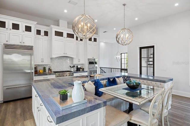 kitchen featuring white cabinets, stainless steel built in fridge, and an island with sink