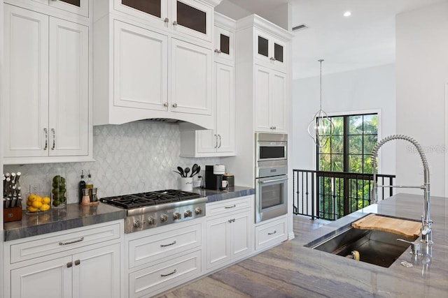 kitchen featuring stainless steel appliances, sink, pendant lighting, light hardwood / wood-style flooring, and white cabinets