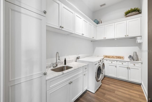 clothes washing area featuring dark hardwood / wood-style flooring, cabinets, separate washer and dryer, and sink