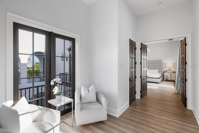 living area with wood-type flooring, a towering ceiling, and french doors