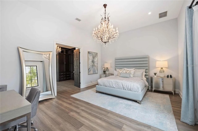 bedroom featuring hardwood / wood-style floors, a walk in closet, and an inviting chandelier