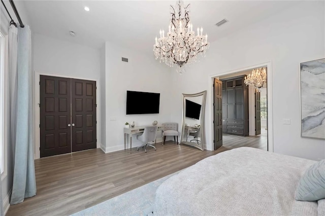 bedroom with hardwood / wood-style flooring, an inviting chandelier, and a closet