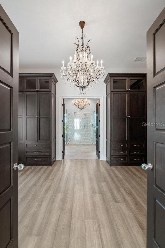 entryway with light hardwood / wood-style flooring and an inviting chandelier