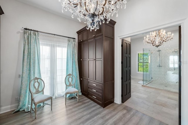 living area featuring plenty of natural light, light hardwood / wood-style flooring, and a chandelier