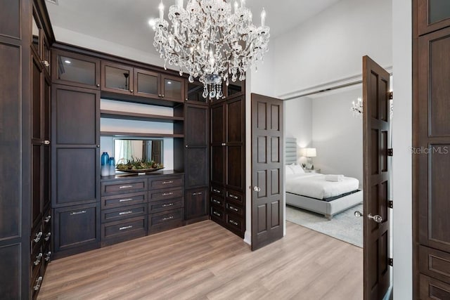 spacious closet with a chandelier, high vaulted ceiling, and light hardwood / wood-style flooring