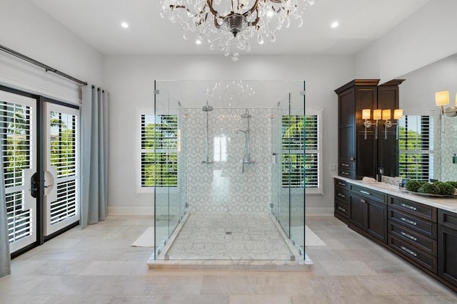 bathroom with a shower with door, vanity, and an inviting chandelier