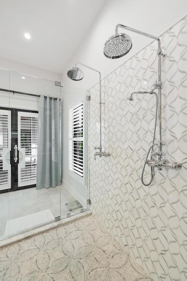 bathroom with tile patterned flooring, a tile shower, and french doors