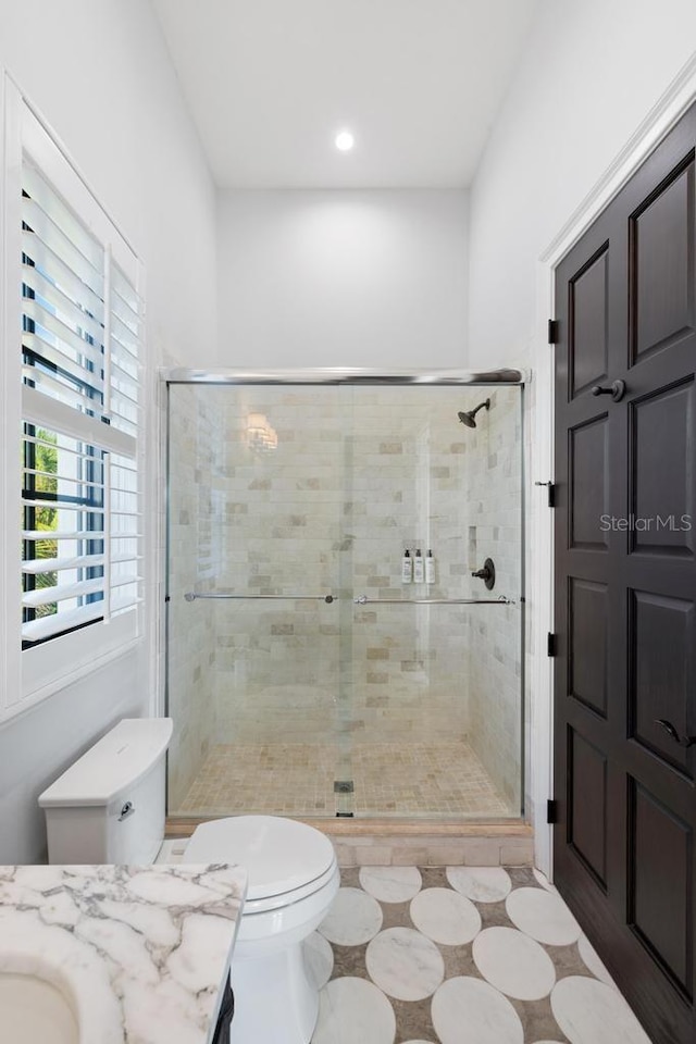 bathroom featuring tile patterned floors, vanity, toilet, and a shower with door