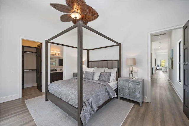 bedroom featuring ceiling fan, dark wood-type flooring, ensuite bathroom, a walk in closet, and a closet